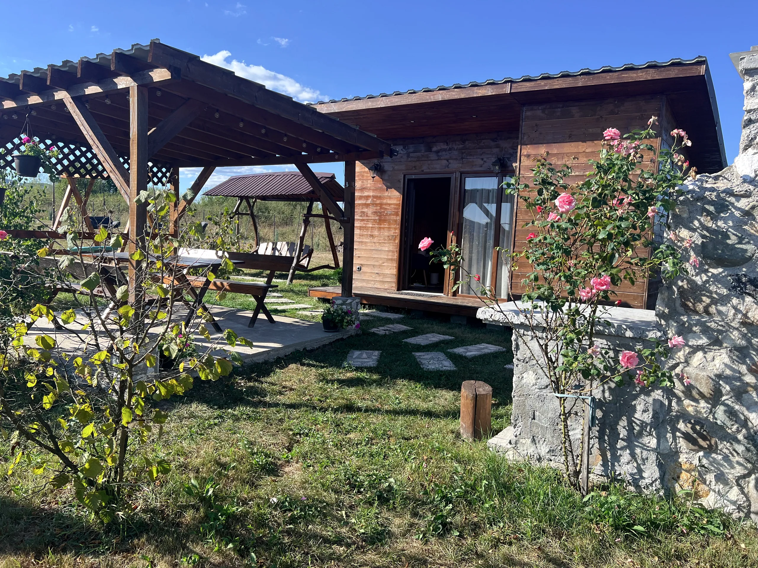 Wooden cabin and pergola framed by roses